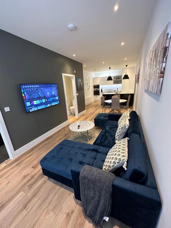 uma sala de estar com um sofá azul e uma televisão de ecrã plano em Hamlet Court Apartments 1A em Southend-on-Sea