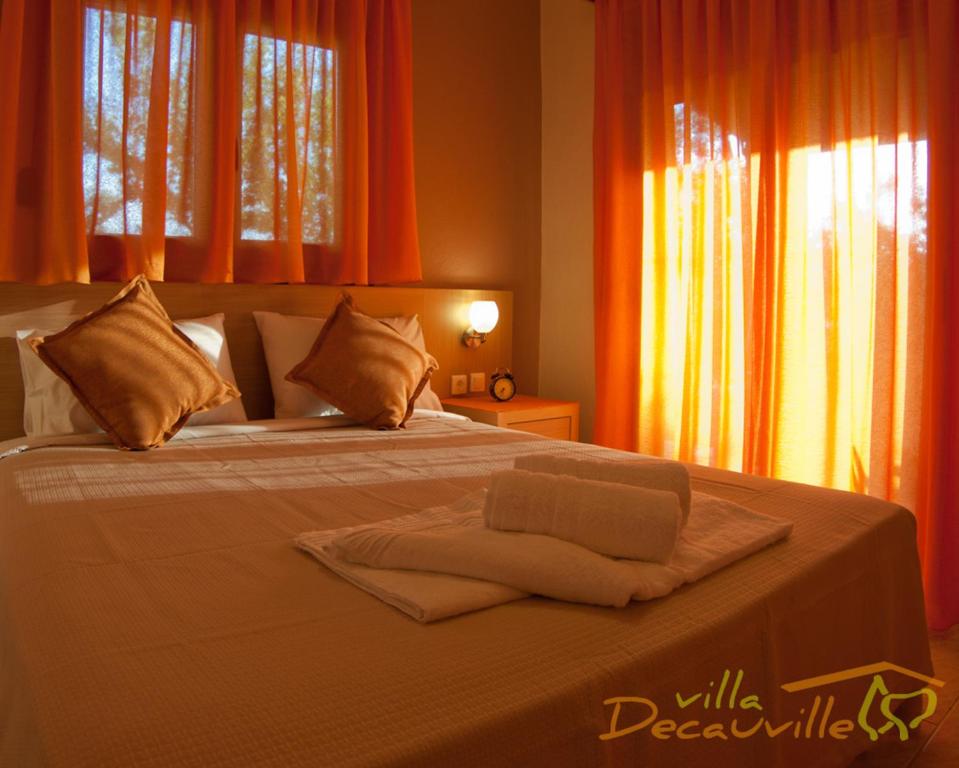 a bedroom with a large bed with orange curtains at Villa Decauville in Gerakini