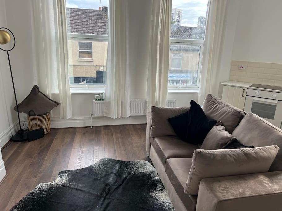 a living room with a couch and two large windows at Forte circle, luxury apartments in South Norwood