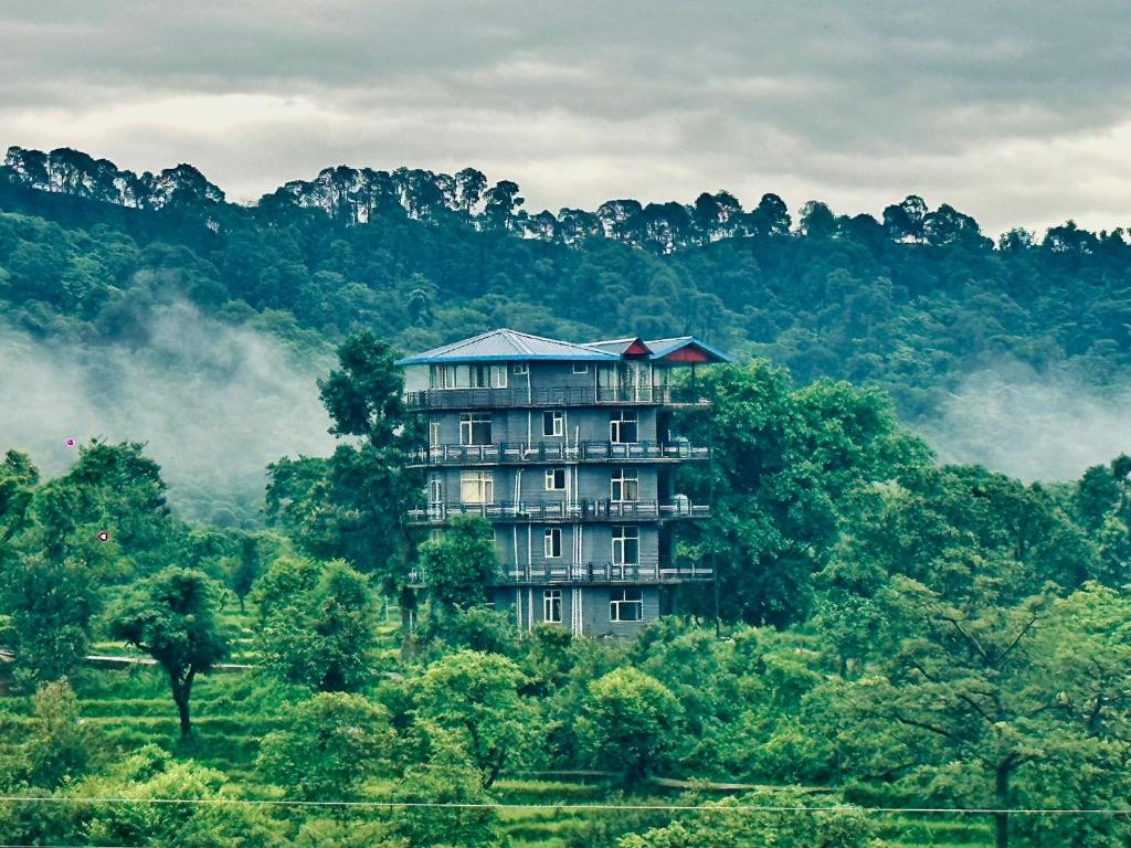 a large building in the middle of a forest at Dhauladhar Homes in Dharamshala