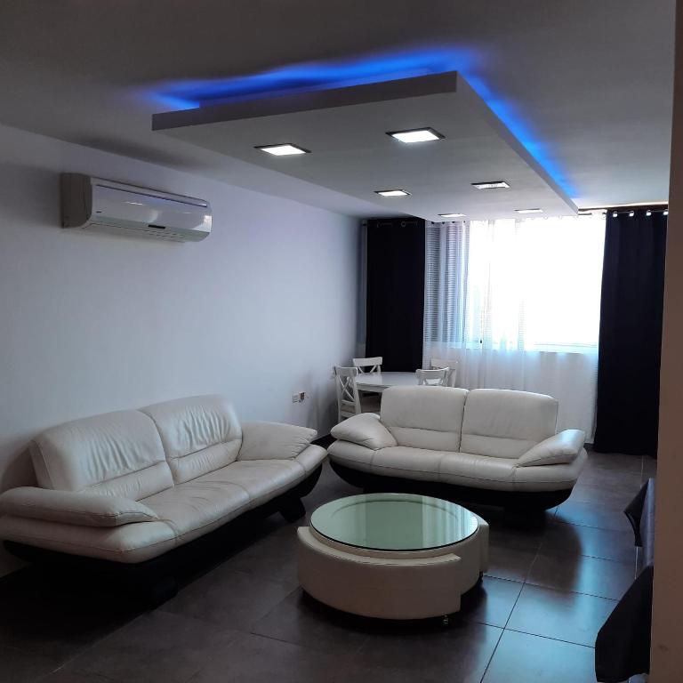 a living room with two white couches and a blue light at yael house in Ashkelon