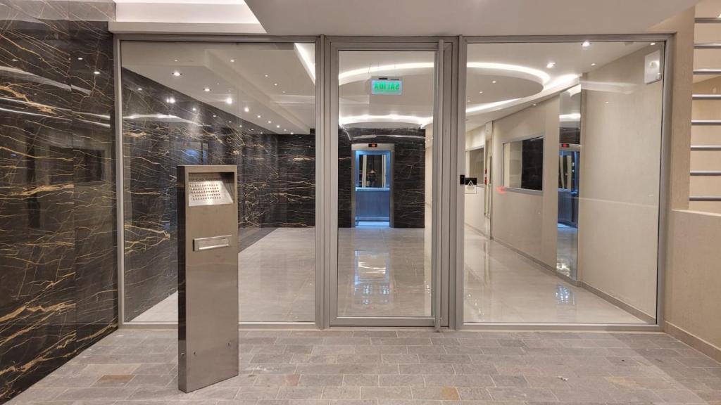 a hallway with glass doors in a building at Departamento moderno con cochera y parrilla, amplio y luminoso in Puerto Madryn