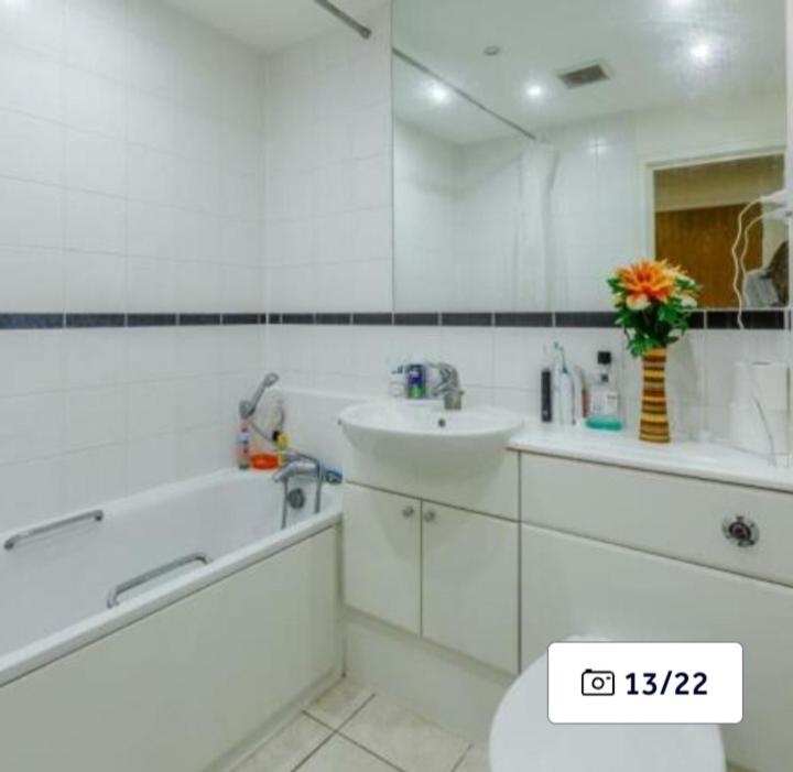 a white bathroom with a sink and a tub and a toilet at Penthouse Experience in South Norwood