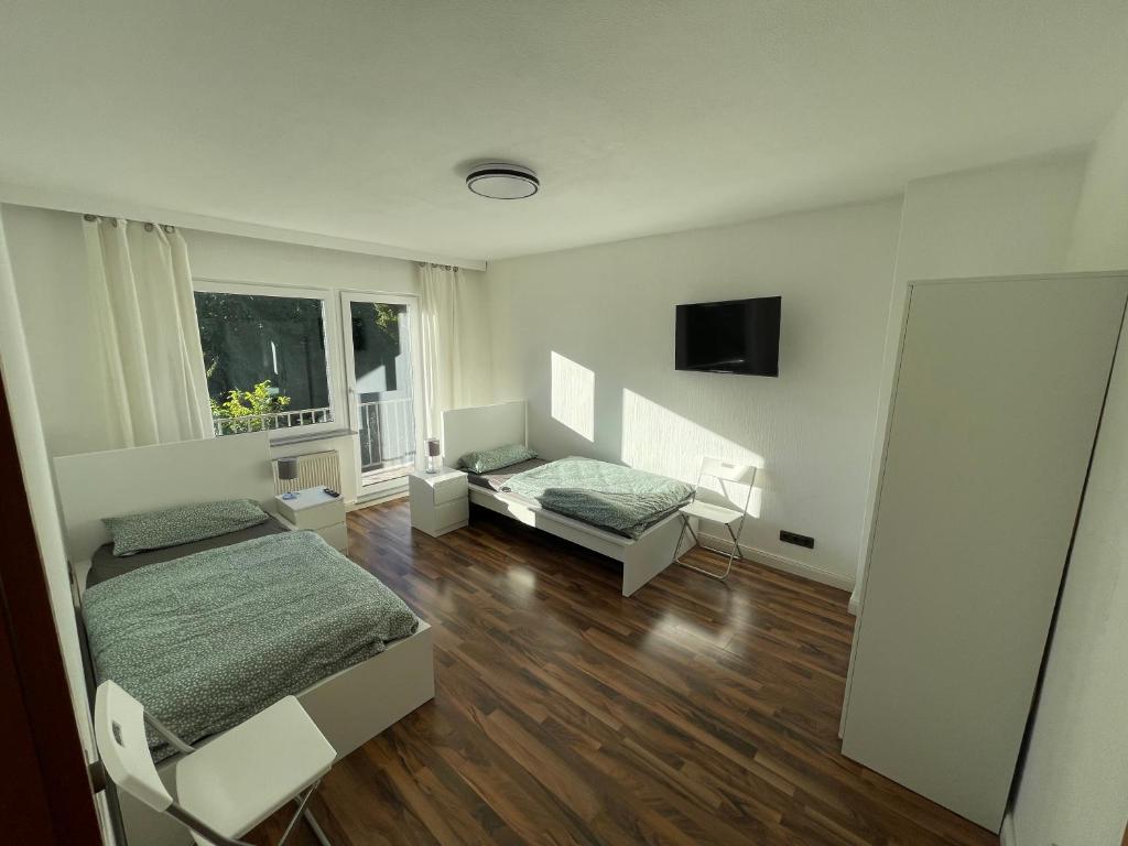 Cette chambre blanche dispose de deux lits et d'une fenêtre. dans l'établissement City Apartment Lux Bremen, à Brême