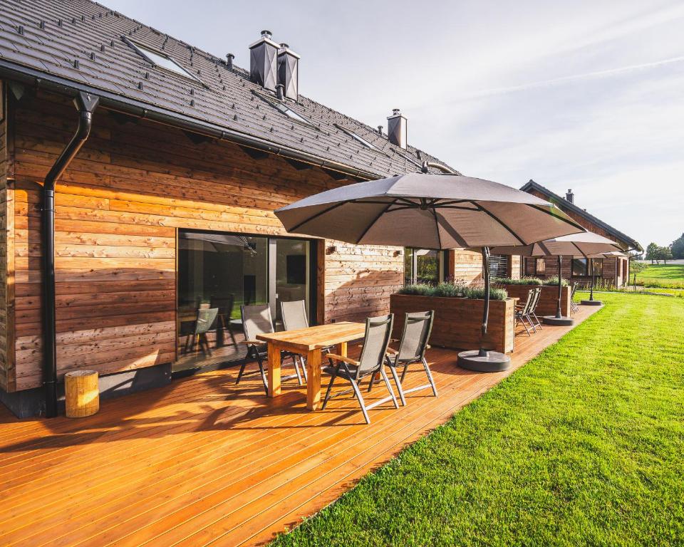 une terrasse en bois avec une table et un parasol dans l'établissement Apartments Schöneben, à Ulrichsberg