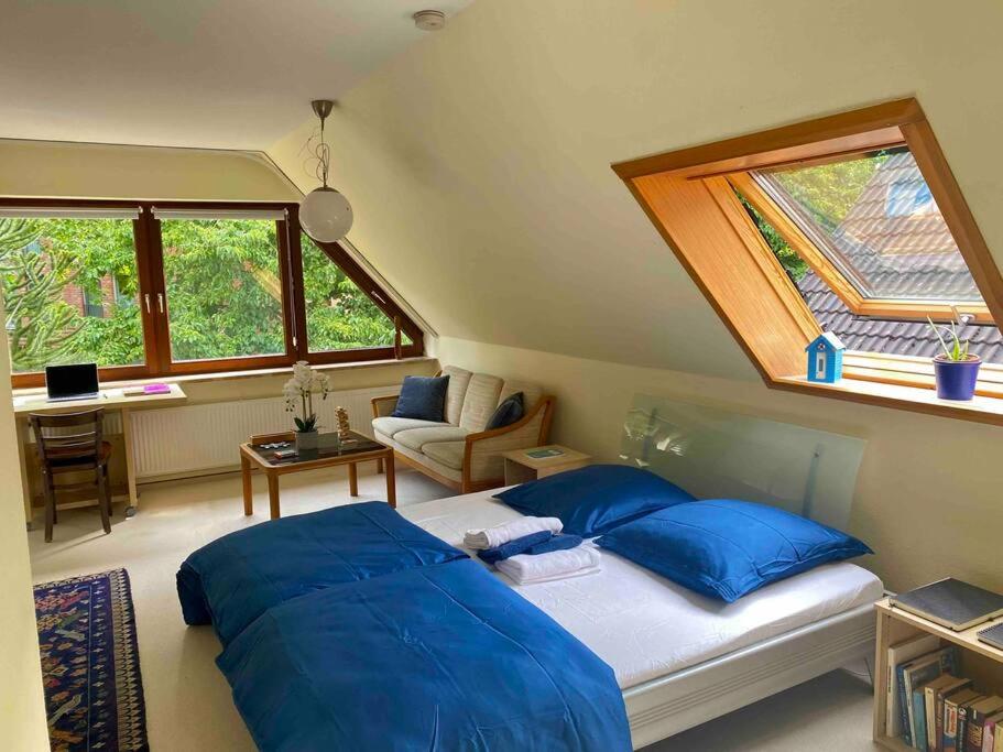a bedroom with a bed with blue sheets and a window at Gartenblick-Oase: Obergeschosswohnung in Hamburg in Hamburg