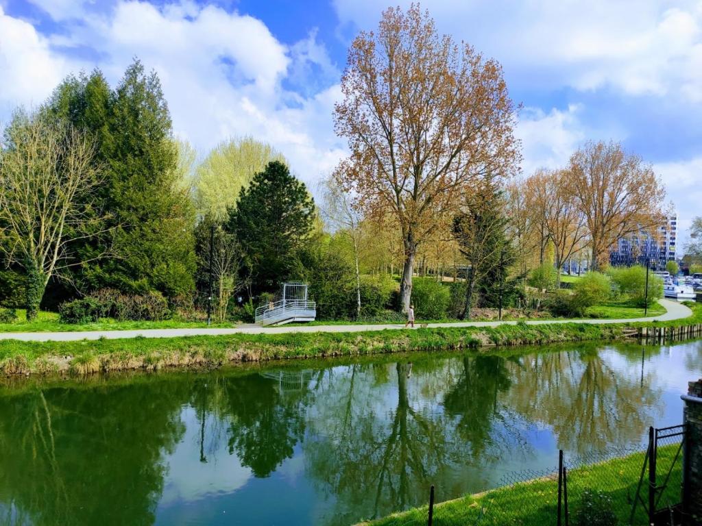 une rivière avec des arbres et un banc à côté dans l'établissement La Waide, à Amiens
