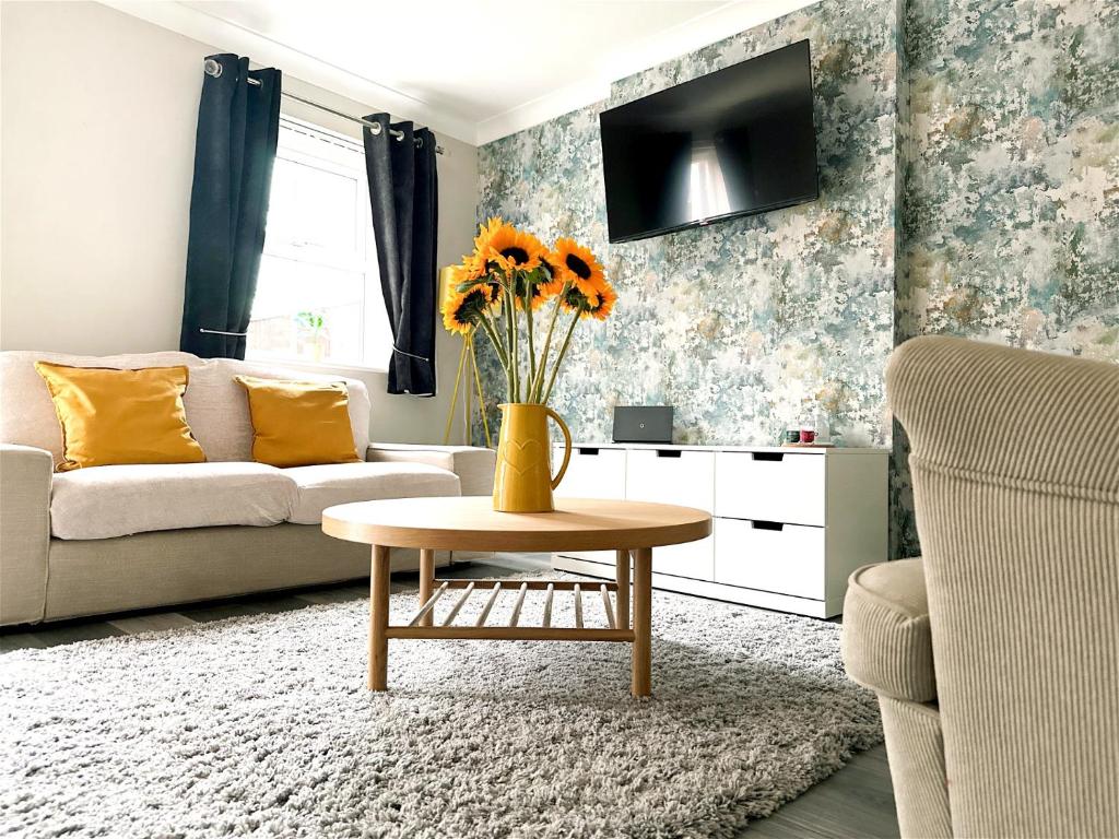 Cheerful two-bedroom townhouse near Leeds and York في ليدز: غرفة معيشة مع أريكة وطاولة مع زهور