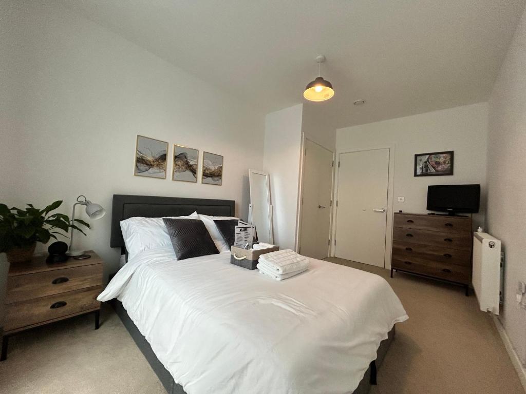 a bedroom with a large white bed and a dresser at My Apartment Brixton - Modern Double Room with En-suite in London