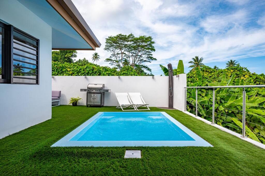 a backyard with a swimming pool and green grass at Sunset Villa Bora in Bora Bora