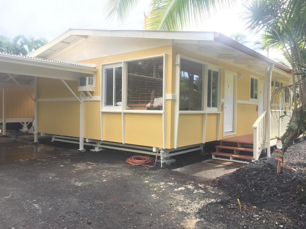 Casa amarilla con porche y ventana en Aaron’s cottage, en Hilo