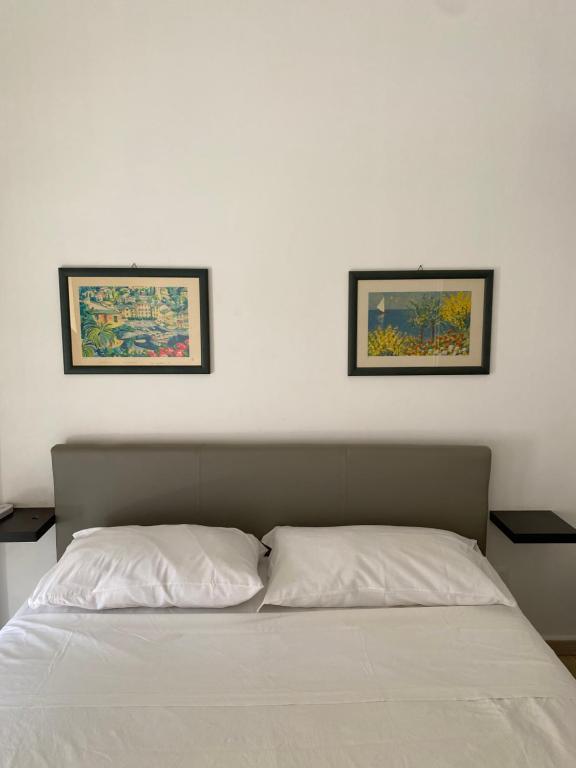 a bed with two pictures on the wall above it at La Masa Apartment in Palermo