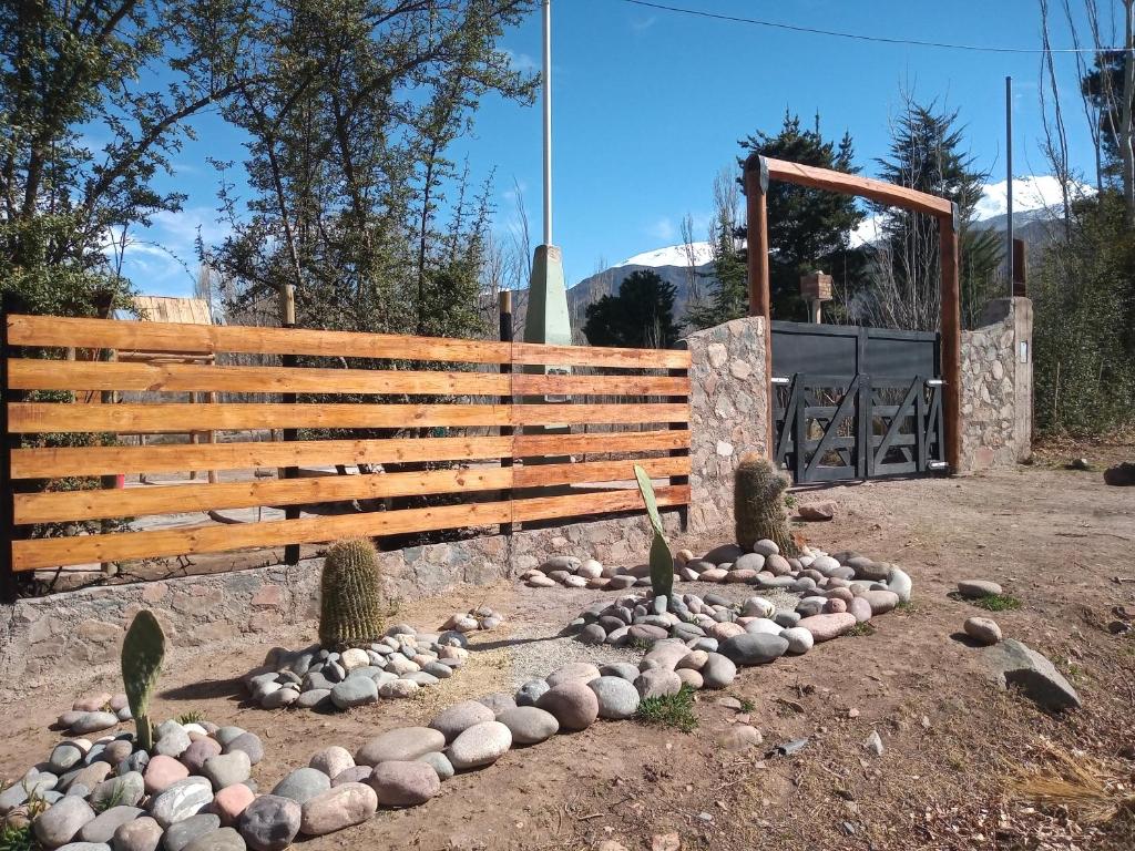 a wooden fence with rocks in front of a gate at Cabañas Rowal in Potrerillos