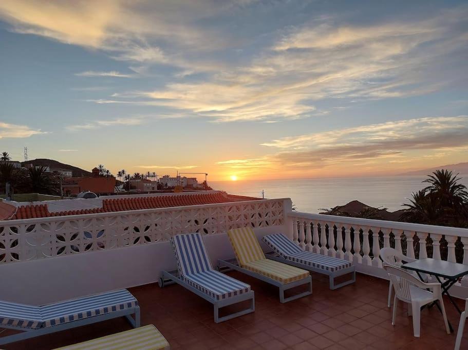 balkon z krzesłami i stołem oraz zachodem słońca w obiekcie Vv Casa Lucas w mieście Vallehermoso