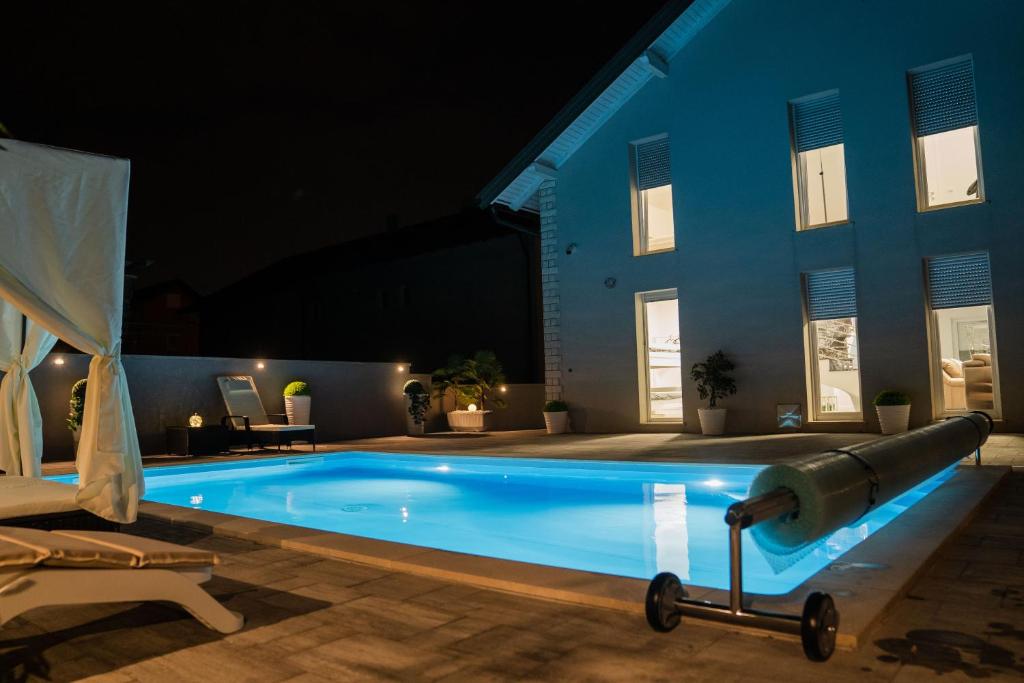 a swimming pool in front of a house at night at Villa J&J in Sesvete