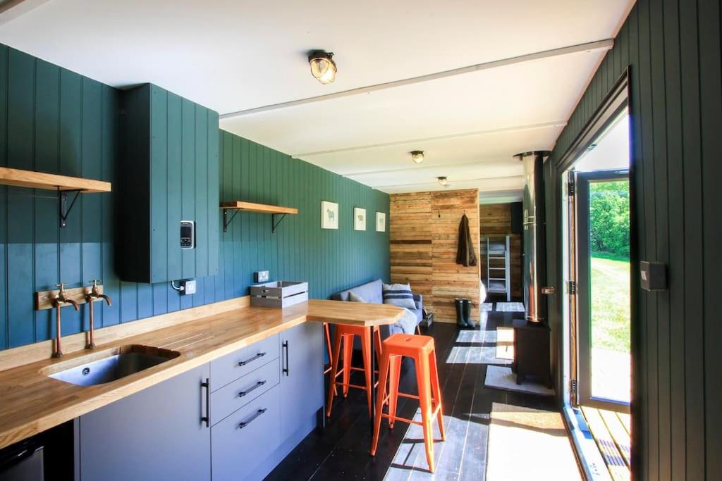 a kitchen with green cabinets and orange bar stools at The Hambleton Hut in Upper Hambleton