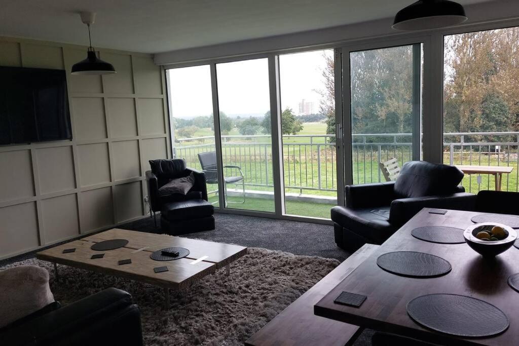 - un salon avec une table, des chaises et une grande fenêtre dans l'établissement 3 Bedroom Apartment with Golf Course View, à Newcastle upon Tyne