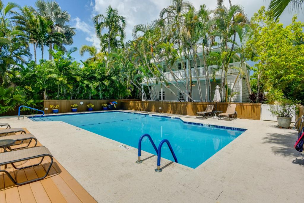 a swimming pool with chairs and palm trees at Breezy Key West First-Floor Condo with Pool Access in Key West