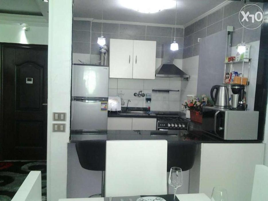 een keuken met witte kasten en een zwart aanrecht bij شقه للإيجار المفروش سوبر لوكس (vip) أمام البحر مباشرة in Alexandrië