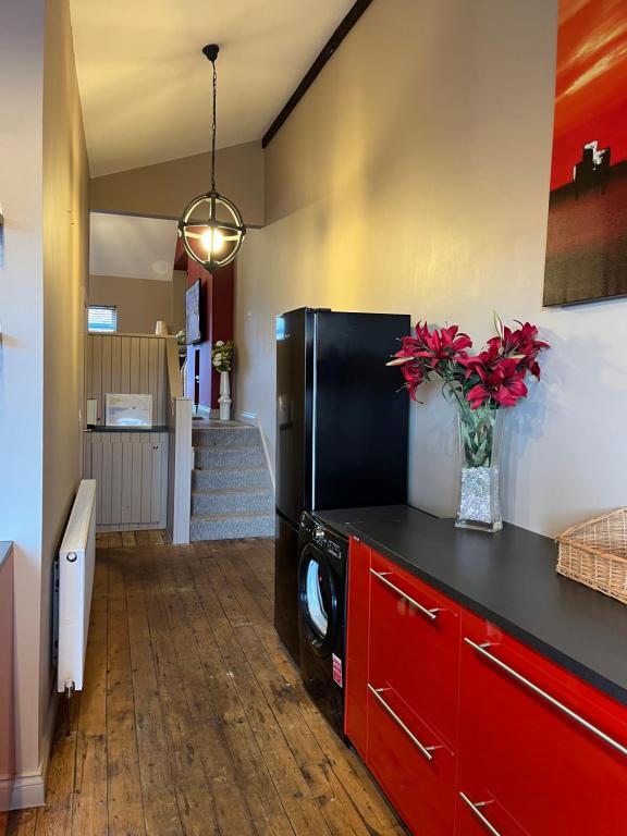 cocina con nevera negra y armarios rojos en APARTMENT 185, en Blackwood