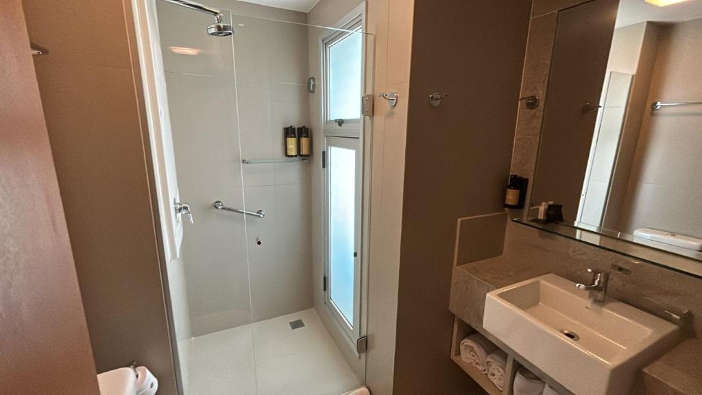 a bathroom with a shower and a sink and a mirror at Jade Hotel Brasília in Brasilia