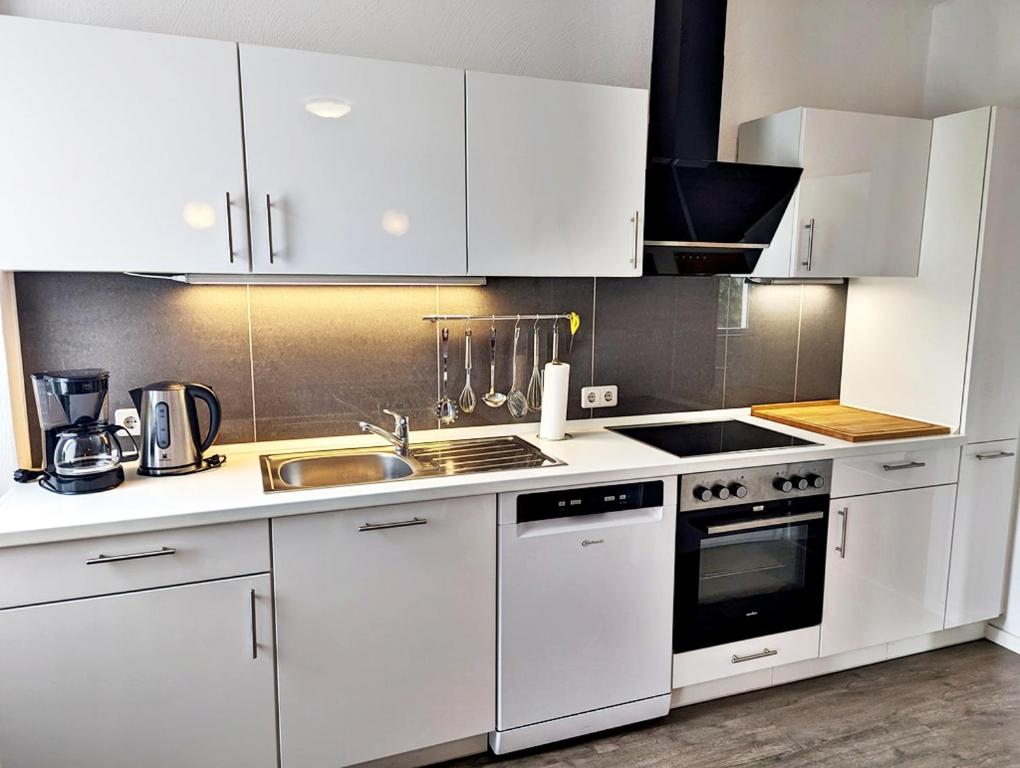 a kitchen with white cabinets and a sink and a stove at Gästehaus Koblenz in Koblenz
