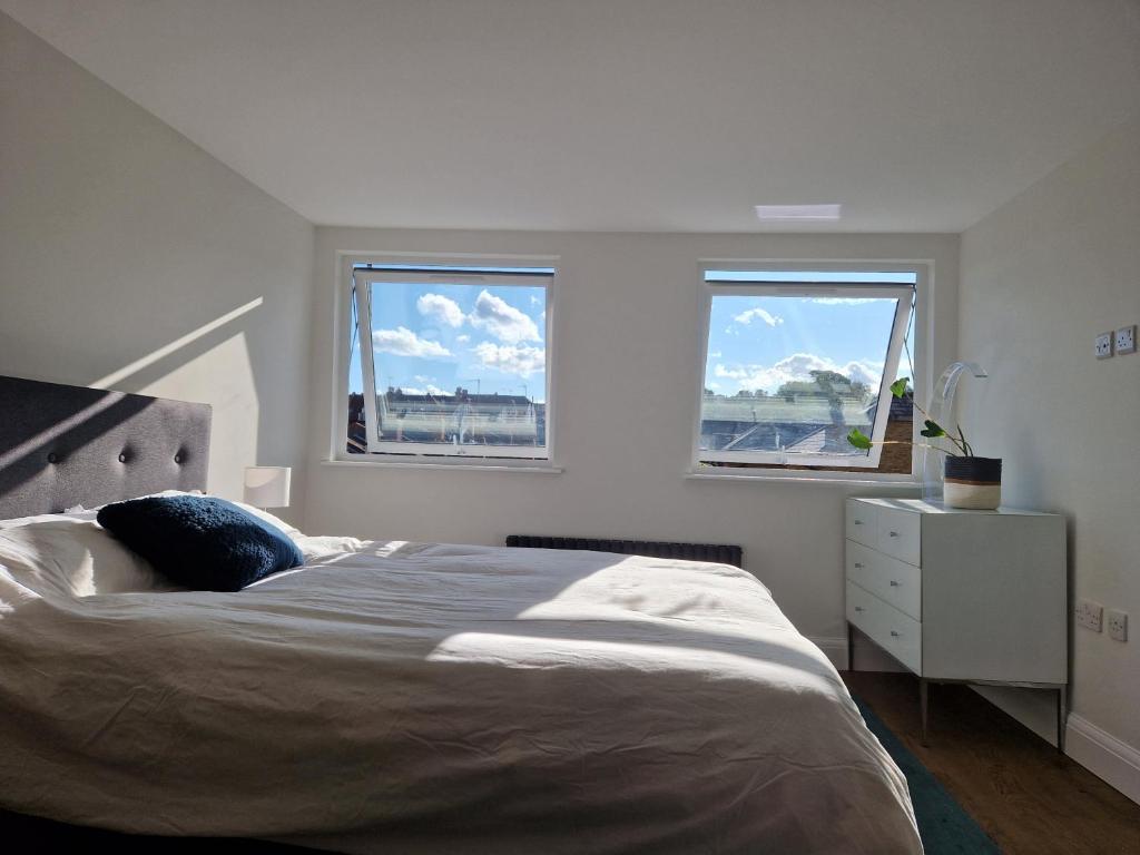 a bedroom with a large bed and two windows at Luxury London Oasis in London