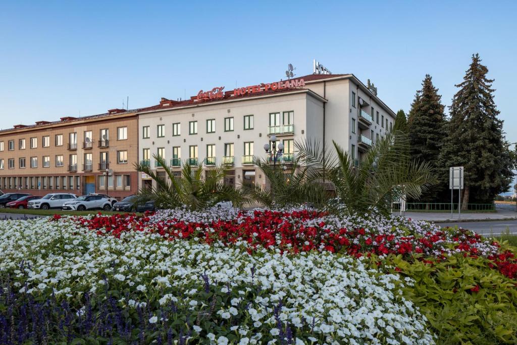 un bâtiment avec un jardin fleuri en face d'un bâtiment dans l'établissement Hotel Polana, à Zvolen