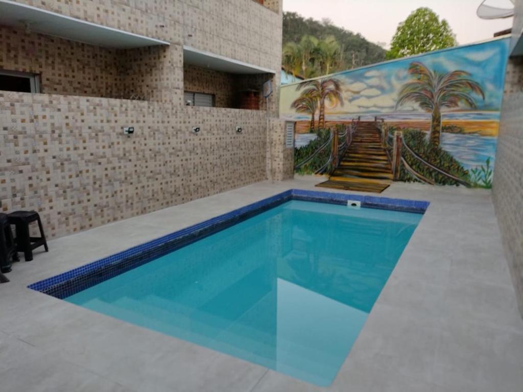 een zwembad in een gebouw met een muurschildering bij Pousada Chales Recanto Sonhos in Ubatuba