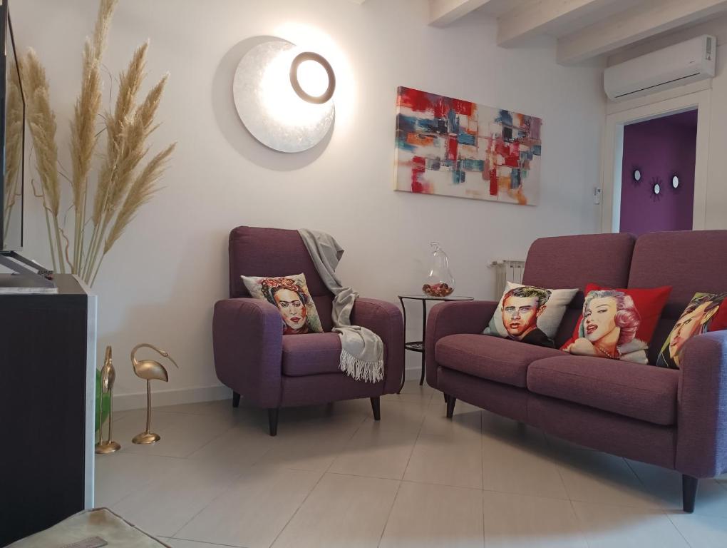 ein Wohnzimmer mit zwei lila Stühlen und einem Sofa in der Unterkunft CIVICO22 in Comacchio