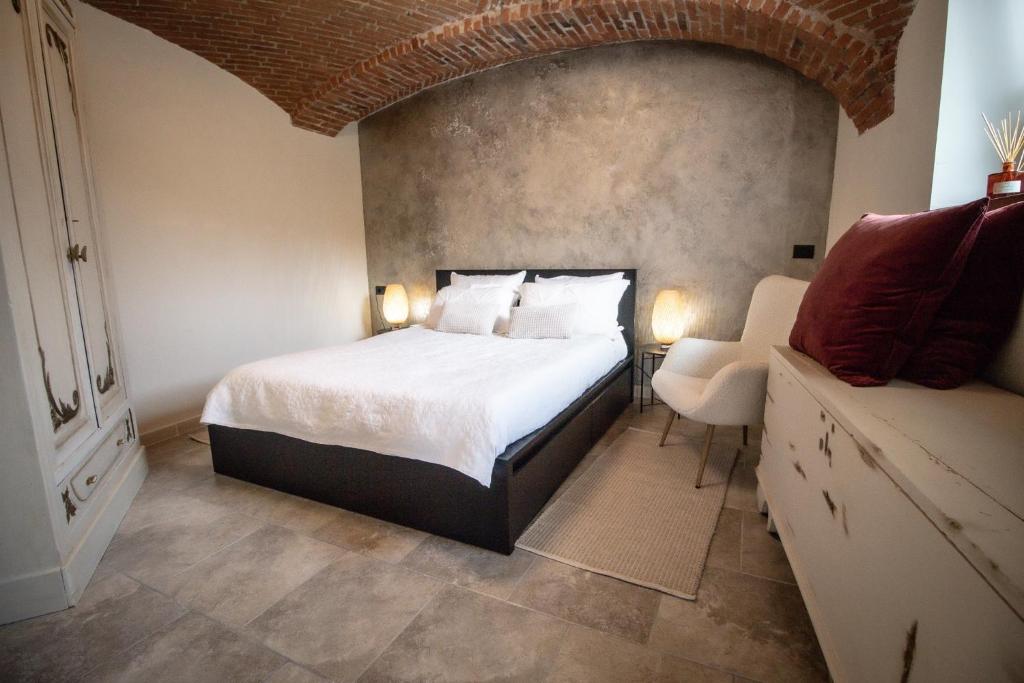 um quarto com uma cama grande e uma cadeira em Le camere del Cappello Verde em Ivrea