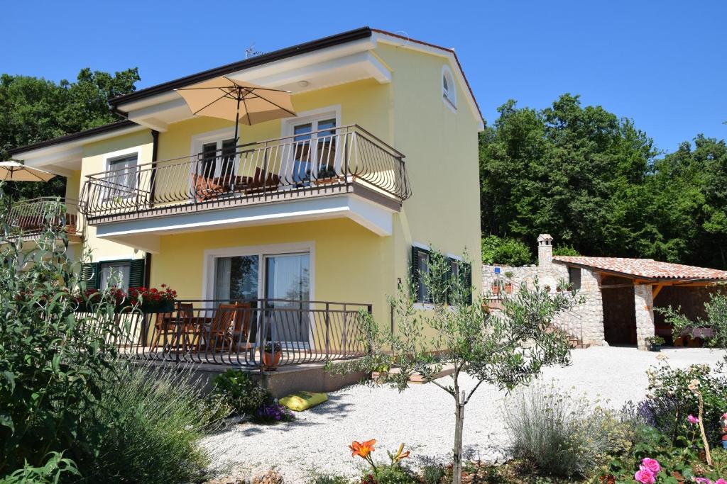 a large yellow house with a balcony and chairs at Apartments Sandra in Brseč