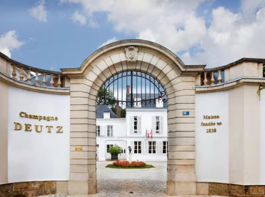an entrance to a white building with an archway at Au cœur du vignoble champenois in Ay