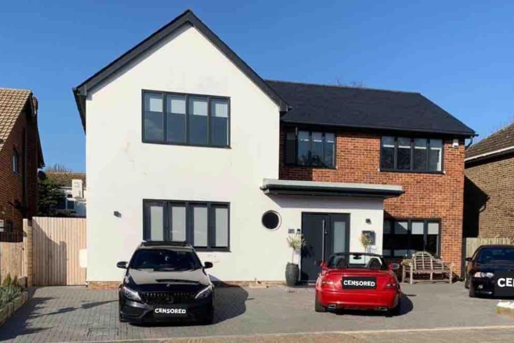 une maison blanche avec deux voitures garées dans un parking dans l'établissement Modern Annex, à Kent