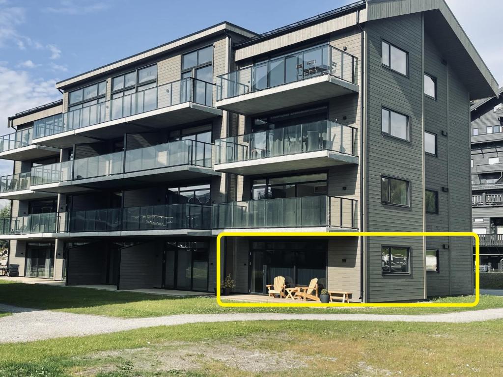 un immeuble d'appartements avec un rectangle jaune devant lui dans l'établissement Highland Lodge Fjellandsby - 3105, à Geilo