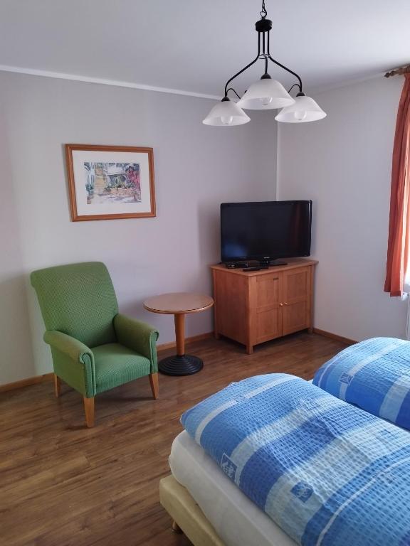 1 dormitorio con 1 cama, 1 silla y TV en pension-Zur alten Bäckerei, en Golßen