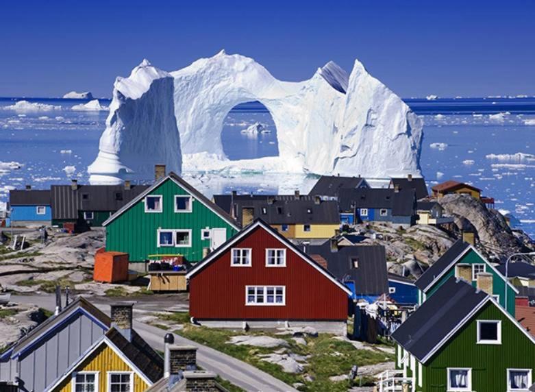 ein Dorf mit Häusern und einem Eisberg im Hintergrund in der Unterkunft B&B Ire in Ilulissat