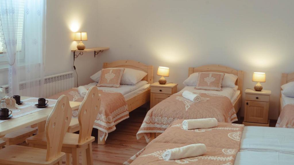 1 dormitorio con 2 camas, mesa y sillas en Noclegi i Agroturystyka Dorota Rusnak en Poręba Wielka