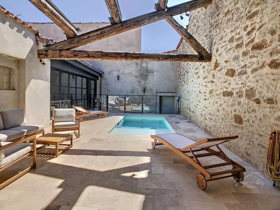 a patio with a swimming pool and chairs and a building at Hidden Oasis - Maison de caractère avec piscine in Azille