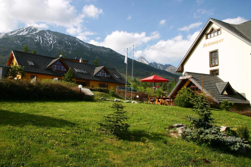 a building with a grass field in front of a house at Reitmayer in Smokovce