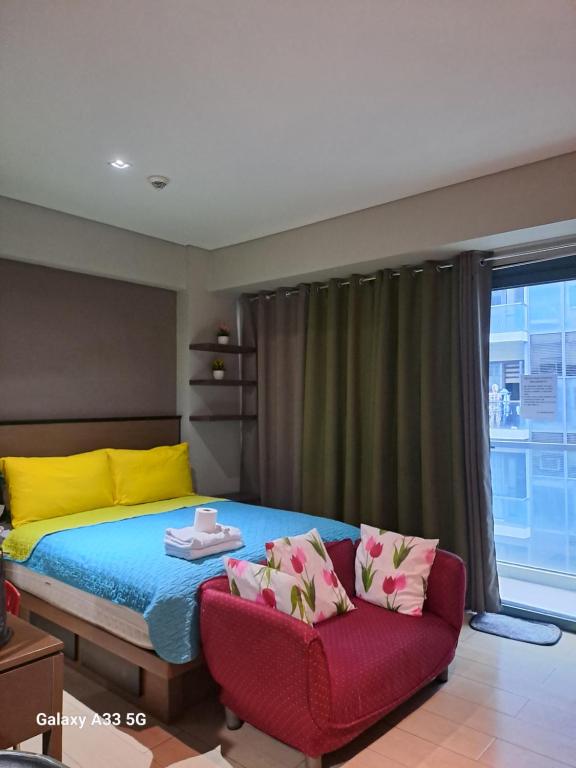 een slaapkamer met een bed en een rode bank bij MRMcondotel in Manilla