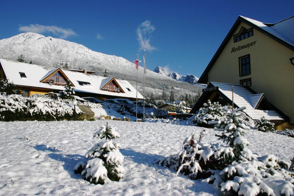 einen schneebedeckten Hof mit Bäumen vor einem Gebäude in der Unterkunft Reitmayer in Nový Smokovec