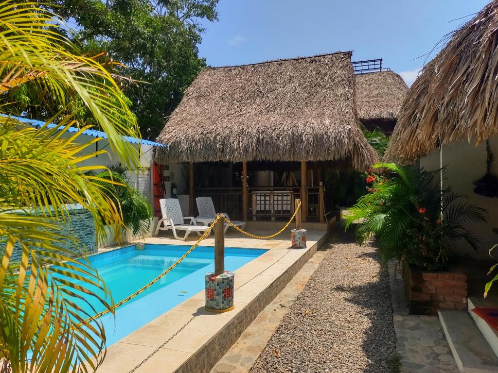 a villa with a swimming pool and a thatch roof at El Leon Feliz Palomino in Palomino