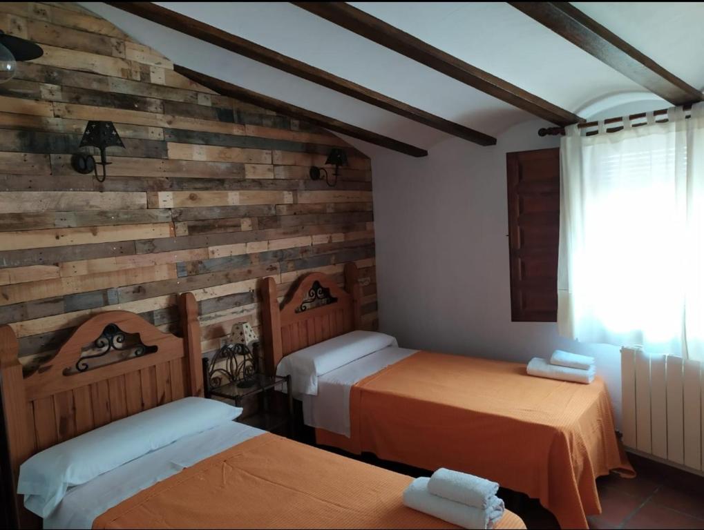 a bedroom with two beds and a wooden wall at Casa Rural El PARADOR in Carcelén