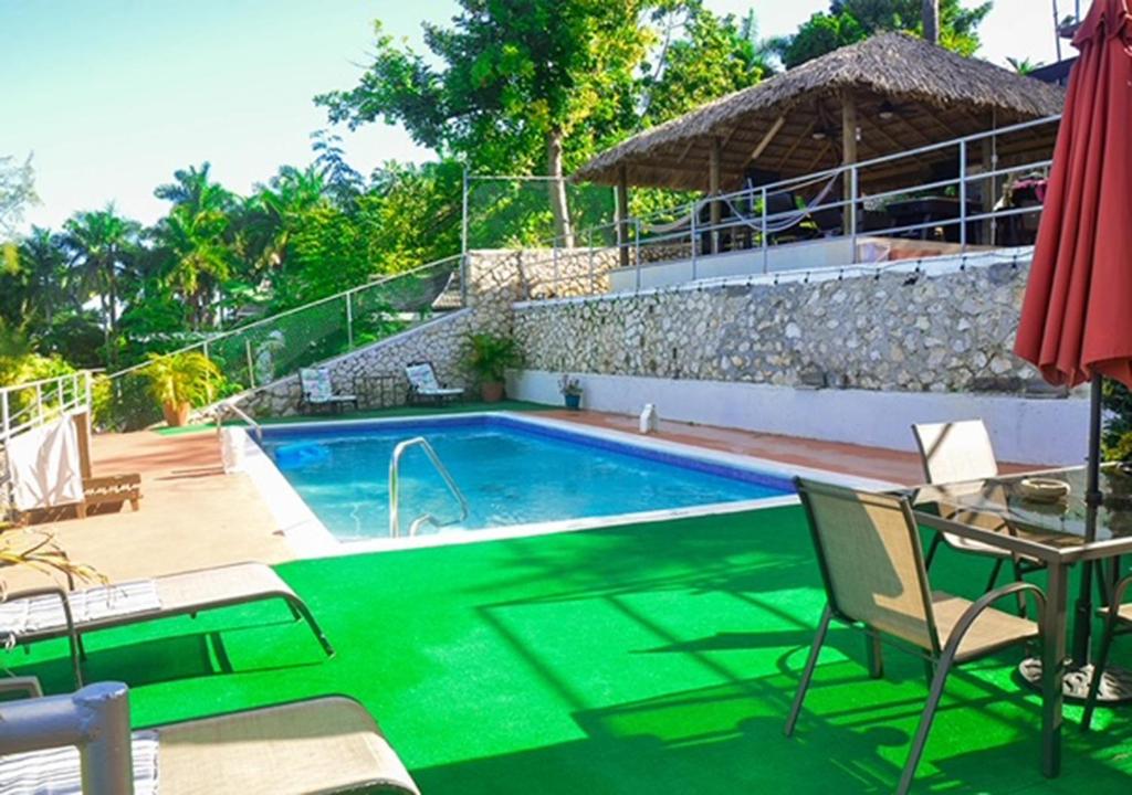 a swimming pool with a table and chairs and a house at Bella Vista Vacation in Montego Bay
