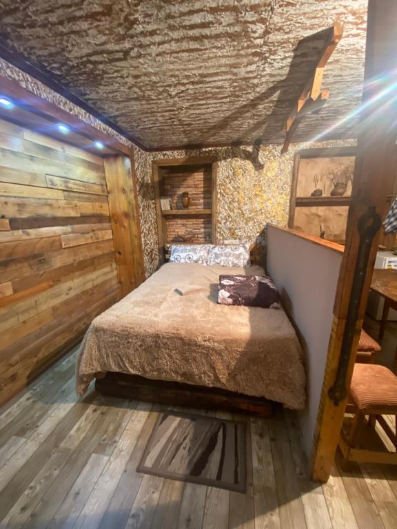 a bedroom with a bed in a room with wooden walls at Xrchit (Խրճիթ) in Gyumri