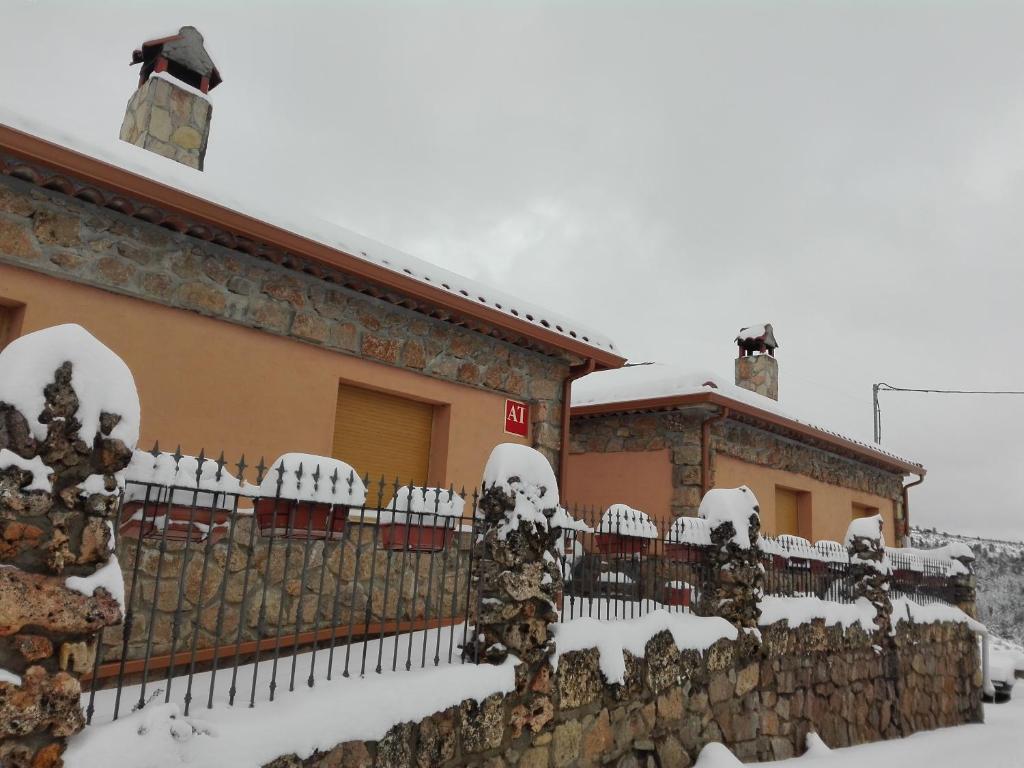 uma cerca coberta de neve em frente a uma casa em Apartamentos Rurales El Tormagal 