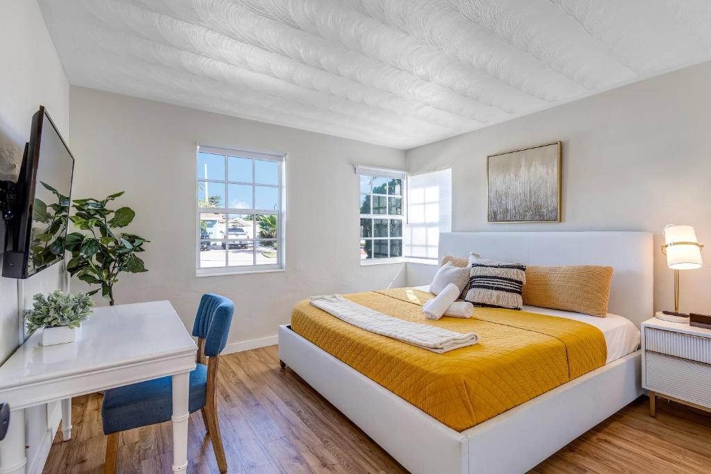 a white bedroom with a bed and a desk at Tropical getaway with coastal charm in Pompano Beach