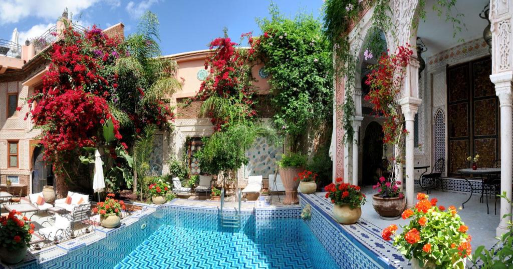 a swimming pool in the courtyard of a building with flowers at Riad Palais Sebban in Marrakech