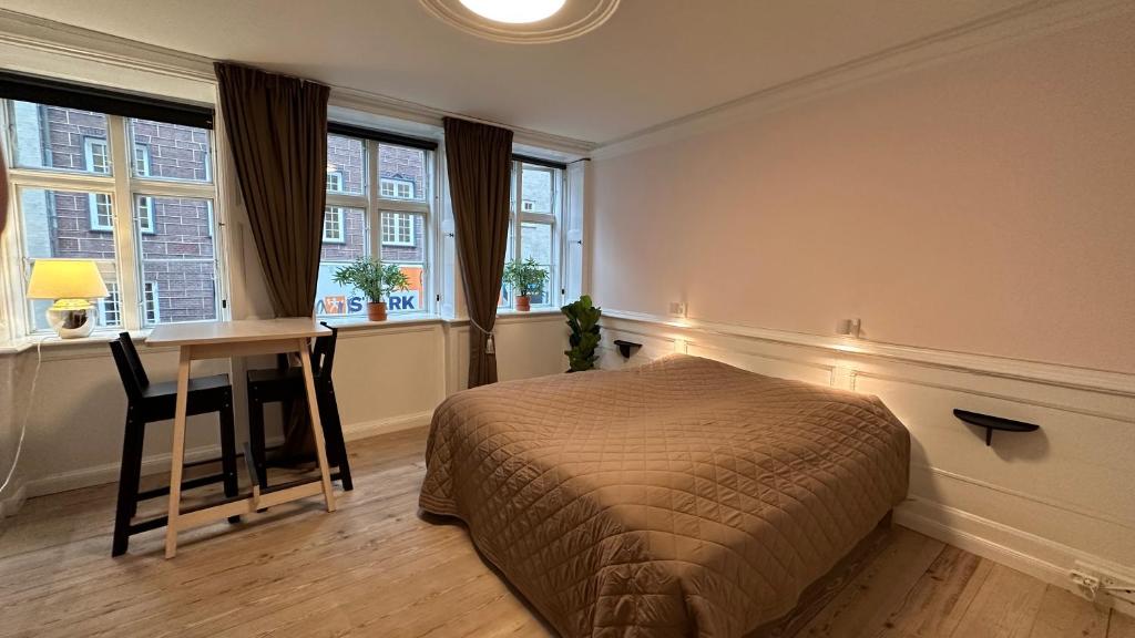 a bedroom with a bed and a desk and windows at Central Canal Apartments 1 - 8 in Copenhagen